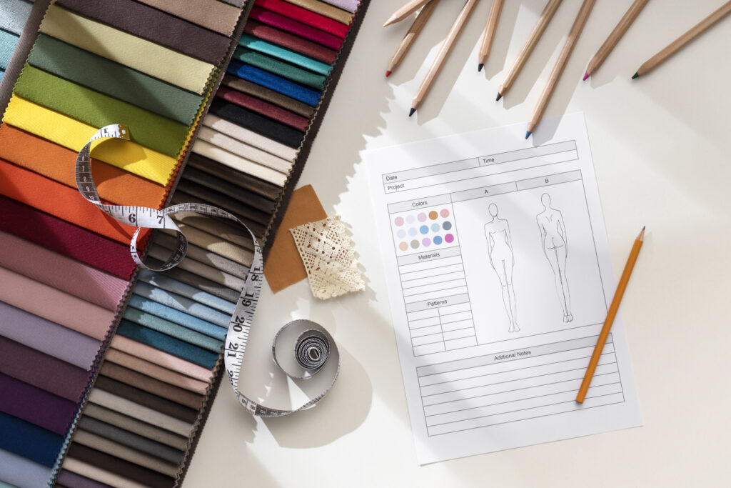 Fashion design desk with fabric swatches, spec sheet, and tools Flat lay of a fashion design workspace featuring colorful fabric swatches, a tech pack template, measuring tape, colored pencils, and lace samples under natural sunlight. Subtle signs of apparel manufacturer mistakes are visibleโsuch as incorrect fabric labels, uneven lace trims, and inconsistent color samplesโhighlighting common production issues faced by designers.