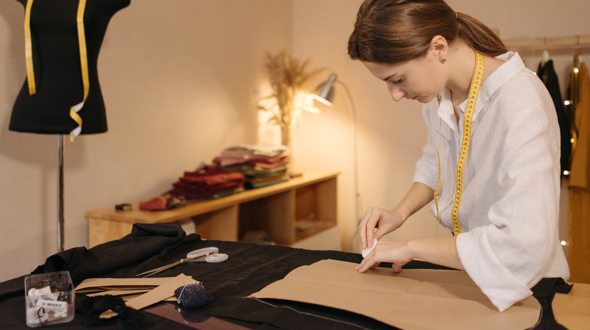 Fashion designer preparing a garment sample with paper pattern on fabric, highlighting hidden costs in apparel manufacturing.
