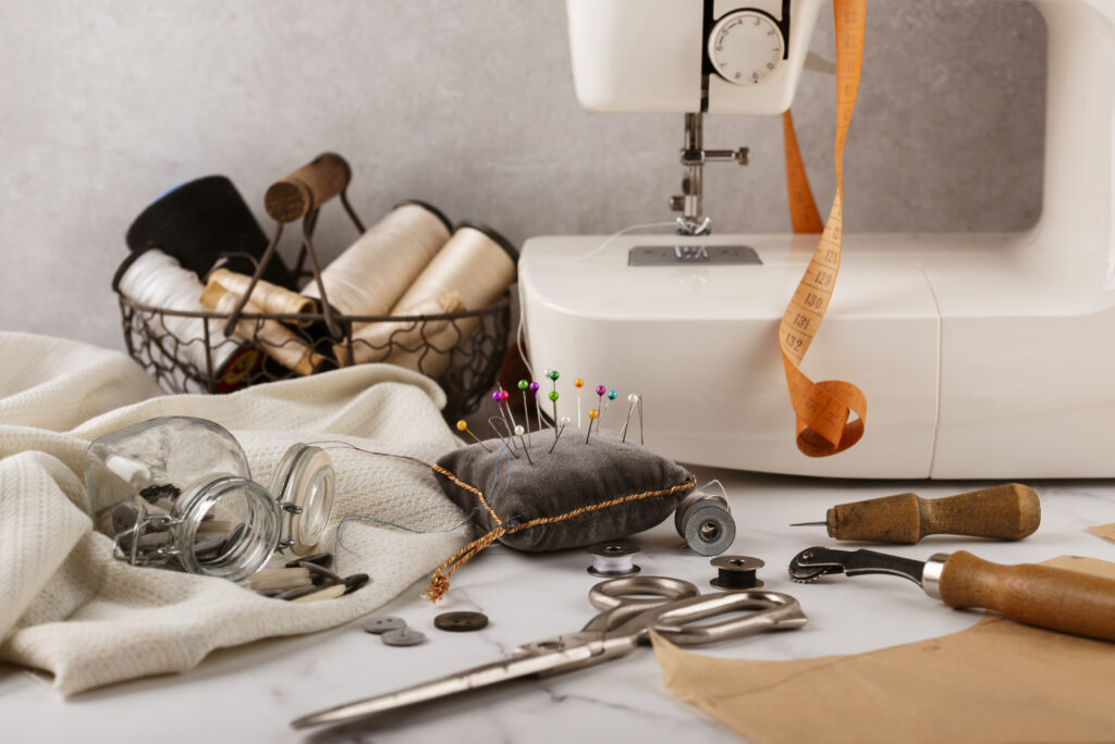 Tailoring workspace with sewing tools, fabric, and measuring tape — illustrating how materials, skill, and design complexity influence apparel sampling cost.