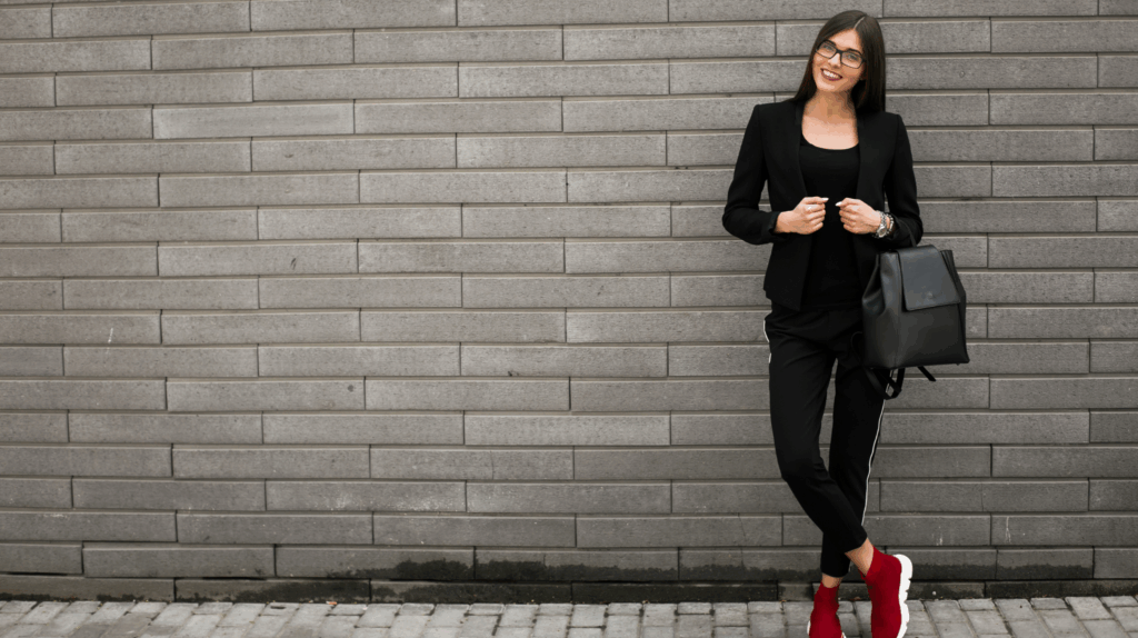 Woman wearing black jogger pants, black tee, black blazer, and sneakers showcasing modular athleisure for hybrid work and lifestyle dressing.