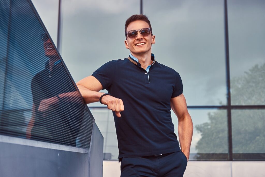 Young fashionable man wearing a black polo shirt in a modern city, illustrating lifestyle and fashion polo styling