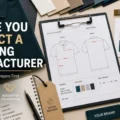 Clothing manufacturer preparation workspace showing a polo shirt, fabric swatches, technical sketch, colour palette, labels, and branding checklist.